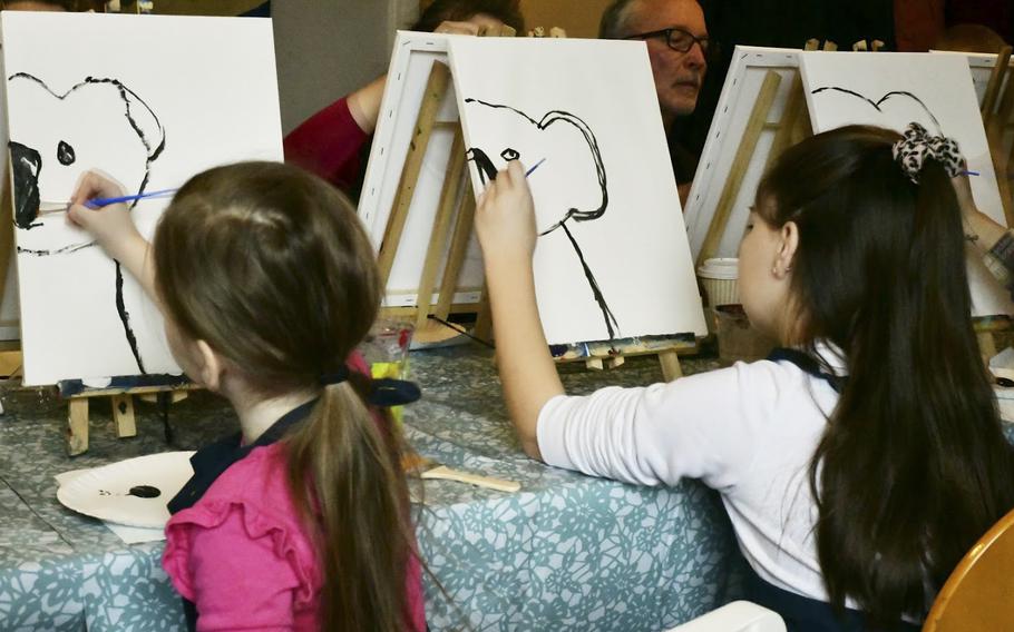 Six-year-old Kat Young, left, and her sister Victoria put the beginning brushstrokes on the koala bears they painted at a fundraiser for victims of the Australian bushfires in Landstuhl, Germany on Saturday, Jan. 25, 2020. 