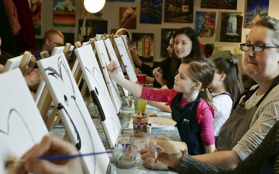 Members of the Kaiserslautern military community  paint the first strokes of koala portraits at a fundraiser for victims of the Australian bushfires, in Landstuhl, Germany, on Saturday, Jan 25, 2020.  