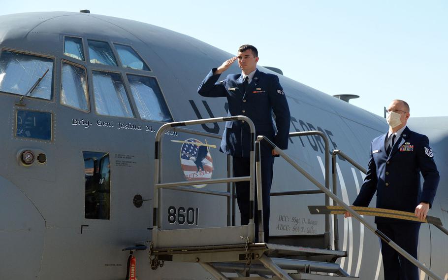 Senior Airman Trevor Gillett salutes the new commander of the 86th Airlift Wing, Brig. Gen. Josh M. Olsen after unveiling his name on a C-130 aircraft during the unit's change of command ceremony at Ramstein Air Base, Germany, Aug. 7, 2020. At right, Tech. Sgt. Sean Taylor holds the nameplate of the outgoing commander, Brig. Gen. Mark R. August.










