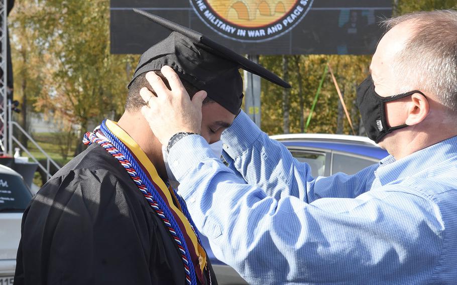 George ReGester adjusts the cap of his son, Stedman ReGester, 21, at the University of Maryland Global Campus Europe commencement ceremony for the class of 2020 on Saturday, Nov. 7, 2020, in Kaiserslautern, Germany. Stedman, who lives in Ansbach, Germany, with his family, received a bachelor's degree in networking security.