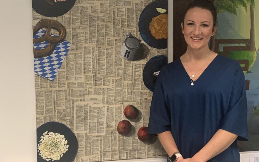 Jenn Clark, an art teacher for the kids' club at Hohenfels Training Area in Germany, poses next to her painting at the acute respiratory center on Dec. 6, 2020. Nine artists contributed art for an exhibition at the coronavirus test center, designed to take patients' minds off the discomforts of being tested for the virus.

