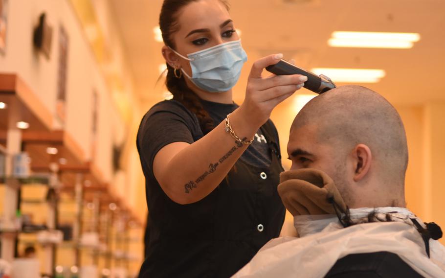 Kaltrian Ibrij shaves off Senior Airman Jeremiah Lamb's hair at the barbershop on Ramstein Air Base, Germany, in May 2020, when it had just reopened after being closed for about six weeks during the first wave of the coronavirus pandemic. Barbershops and beauty salons on U.S. military bases in Germany were closed again in December because of the virus, but will reopen March 1.

