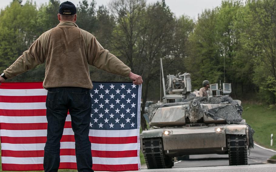 A German holding an American flag greets U.S. vehicles assigned to the 2nd Armored Brigade Combat Team, 1st Infantry Division as they move from Grafenwoehr Training Area to Hohenfels, Germany, in 2018. Germany contributed $118 million to support foreign troop missions in the country in 2020.