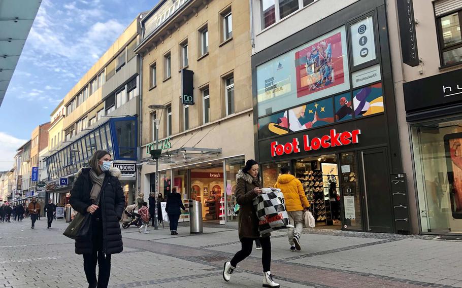 People walk past open shops in the pedestrian area of Kaiserslautern, Germany, on March 23, 2021. The German federal government and states announced Tuesday, after a 15-hour virtual meeting, that most shops will be shuttered for five days over Easter, as part of measures to try to stop an uptick in the spread of the coronavirus.


