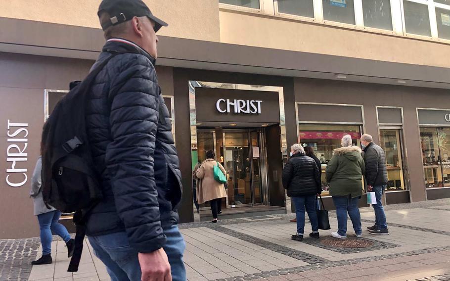 Customers stand outside Christ jewelers in Kaiserslautern's pedestrian zone on March 23, 2021. 
