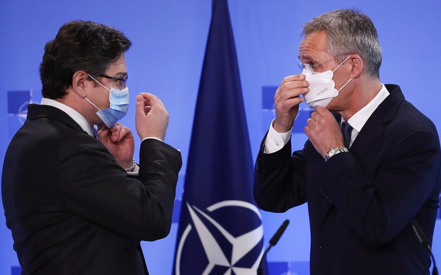 NATO Secretary General Jens Stoltenberg, right, and Ukraine's Foreign Minister Dmytro Kuleba put on their protective face masks after addressing a media conference at NATO headquarters in Brussels, Tuesday, April 13, 2021. Stoltenberg and Kuleba met to discuss Russia's troop buildup troops along the frontier with Ukraine.