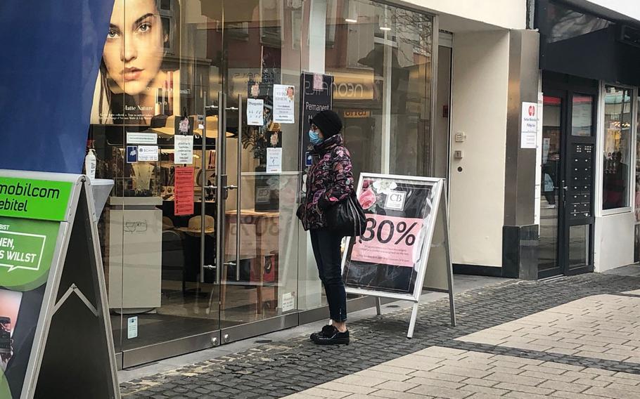 A woman stands outside a cosmetics store in Kaiserslautern on April 19, 2021. 
