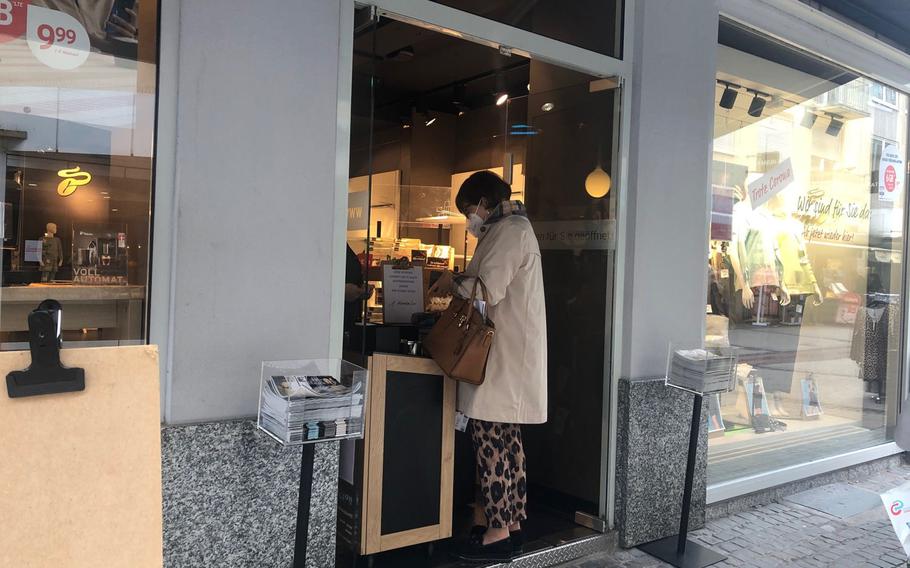 A woman pays for coffee at the Tchibo store in Kaiserslautern on April 19, 2021. The store was allowing in one customer at a time as new coronavirus infections surged in the area.

