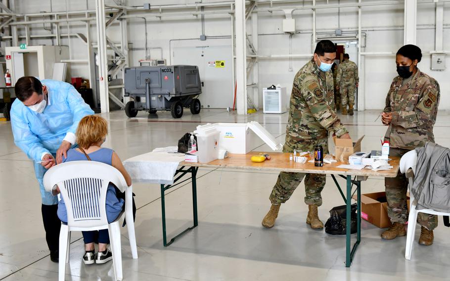 U.S. airmen assigned to the 31st Medical Group prepare syringes with the Moderna COVID-19 vaccine while a local national employee of the base receives her first dose at Aviano Air Base, Italy, April 30, 2021. 

