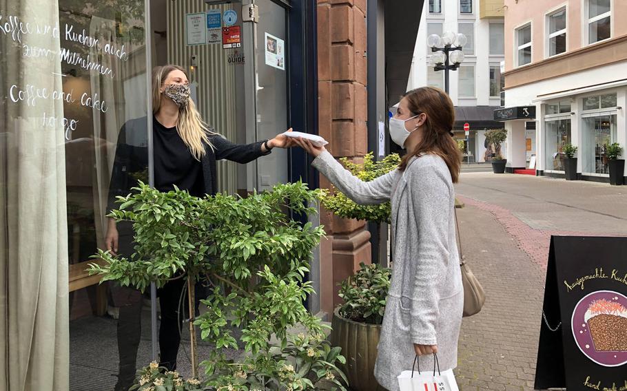 A customer picks up a slice of cake at Cafe Susann in Kaiserslautern, Germany, during the first wave of the coronavirus, May 8, 2020. A year later, Germany was in a third wave of the virus and most eateries were still doing takeout only. 
