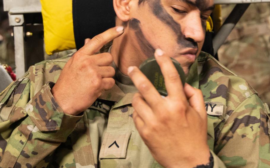 A paratrooper with the 3rd Brigade Combat Team, 82nd Airborne Division, applies face paint onboard a U.S. Air Force C-17 Globemaster III bound for Estonia during Swift Response, May 7, 2021.