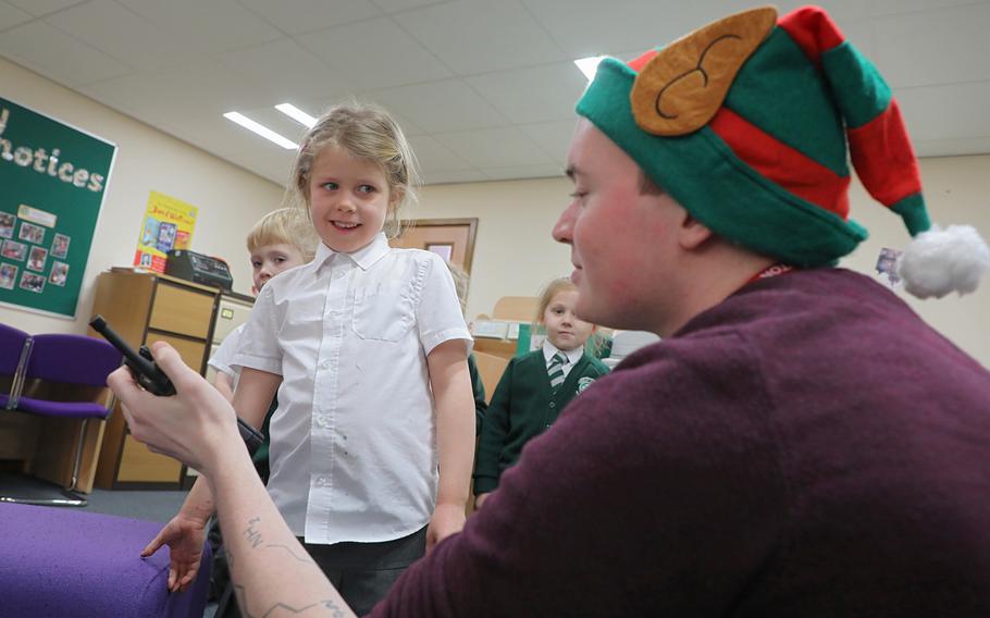 Amber Ramsey, 5, talks to Santa over a handheld radio held by Troy Knoke, a volunteer from the 48th Communications Squadron, Dec. 13, 2019, at Great Heath Academy in Mildenhall, England. 
