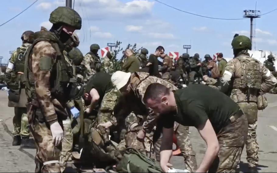 In this photo taken from video released by the Russian Defense Ministry on Friday, May 20, 2022, Russian servicemen frisk Ukrainian servicemen after they leave the besieged Azovstal steel plant in Mariupol, in territory under the government of the Donetsk People's Republic, eastern Ukraine. 