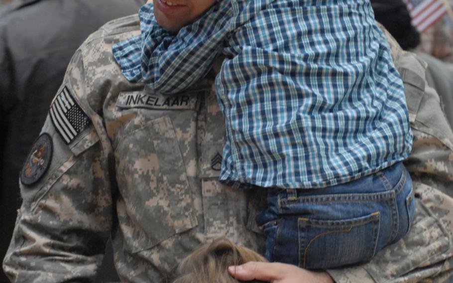 Staff Sgt. Toric Inkelaar holds onto his son Michael, 3, as his other two children, Matthew, 4, and Lucina, 9, embrace their father at the welcome home ceremony for the ''Old Ironsides'' advance party Tuesday night at the Wiesbaden Fitness Center.