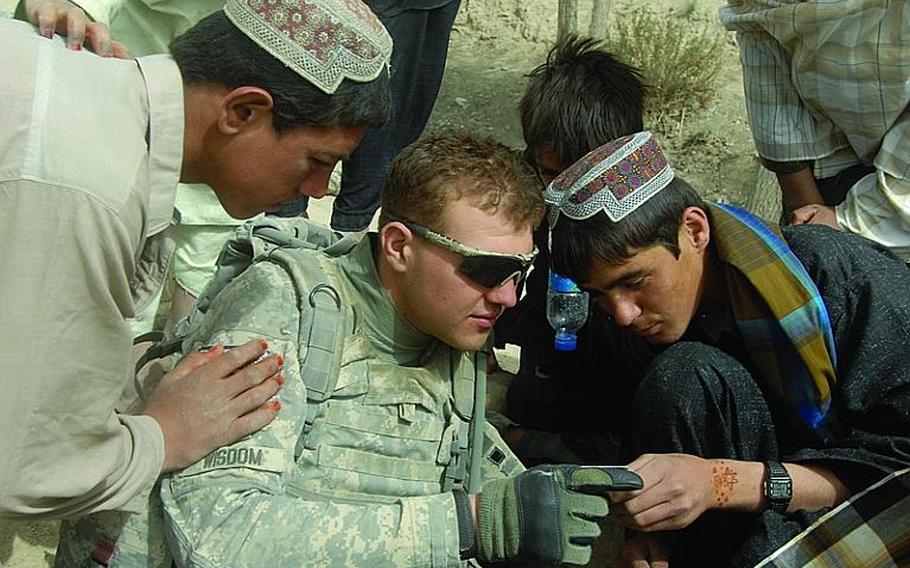 Pfc. Nicholas Wisdom of the 2nd Stryker Cavalry Regiment shows teenagers in Latek village his U.S. Army ID card during a patrol in September, 2010. Wisdom's unit, which deployed in May 2010, will be coming home a little earlier than planned, the brigade commander announced this week.