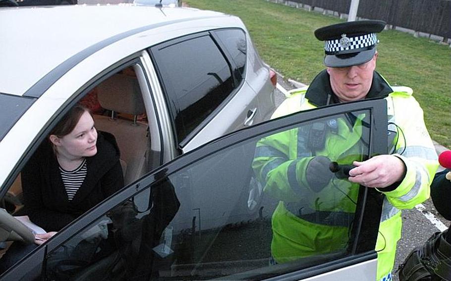 Police Constable Paul Glover with the Ministry of Defence police department at RAF Mildenhall checks the level of tint on the car of  Melissa McKenzie at the main gate of RAF Mildenhall, England. Authorities in Suffolk County are conducting a 30-day amnesty program to allow people with excessively tinted windows to get them checked free of penalty. Glover found McKenzie's window tint to be too dark and above the legal limit of 30 percent tint.