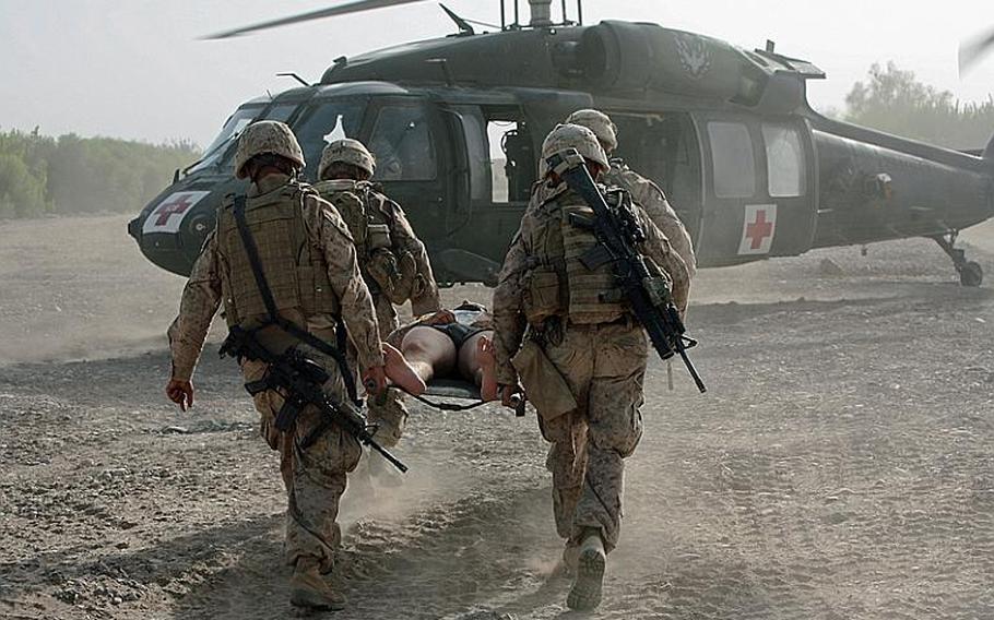 Marines carry a comrade wounded in a bomb blast to a waiting medevac helicopter during combat operations in Helmand Province, southern Afghanistan. July 14, 2009