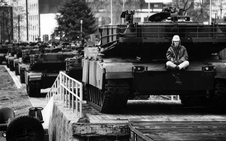 Margaret Wolfe, a driver for the Movement Section, 1st Combat Equipment Company, sits on an M1A1 tank, awaiting the order to drive it onto a rail car at Mannheim, Germany, for shipment to Saudi Arabia by way of Bremerhaven in November, 1990.