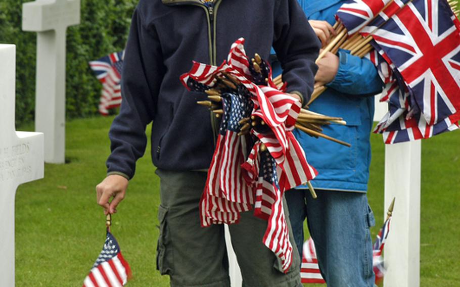 Mike Winters, foreground, and Ethan Schneider, members of RAF Mildenhall's Boy Scout Troop 215, plant a U.S. flag and British flag at each headstone on Friday at the Cambridge American Cemetery and Memorial. About 10 Boy Scouts joined active-duty servicemembers in placing flags at 3,812 gravesites.