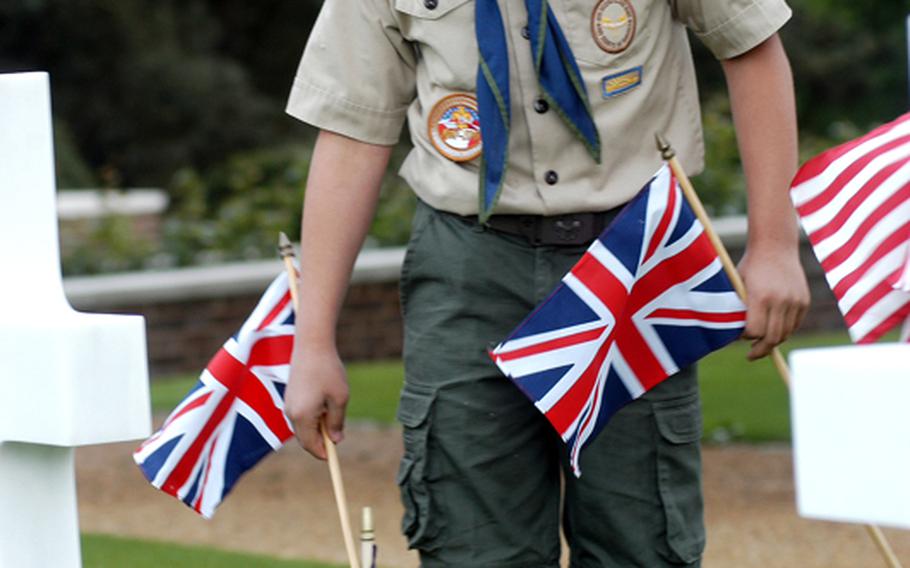 Tim Winters, a Boy Scout with RAF Mildenhall's Troop 215, places a British flag before a headstone at the Cambridge American Cemetery and Memorial in Mondau. Winters, along with other Boy Souts and active-duty servicemembers, planted flags on 3,812 graves.