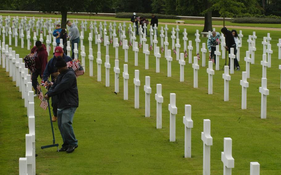 Volunteers at the Cambridge American Cemetery and Memorial place British flags and American flags at each of the 3,812 grave markers in preparation for a Memorial Day ceremony on Monday.