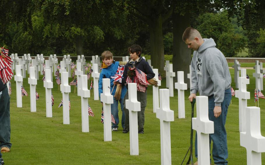 Staff Sgt. Kelly Adle, right, teams with Boy Scouts Mike Winters, center, and Ethan Schneider of RAF Mildenhall's Troop 215 to place flags on the graves of fallen U.S. servicemembers in preparation for a Memorial Day ceremony on Monday. Adler is assigned to the Defense Courier Station at RAF Mildenhall.
