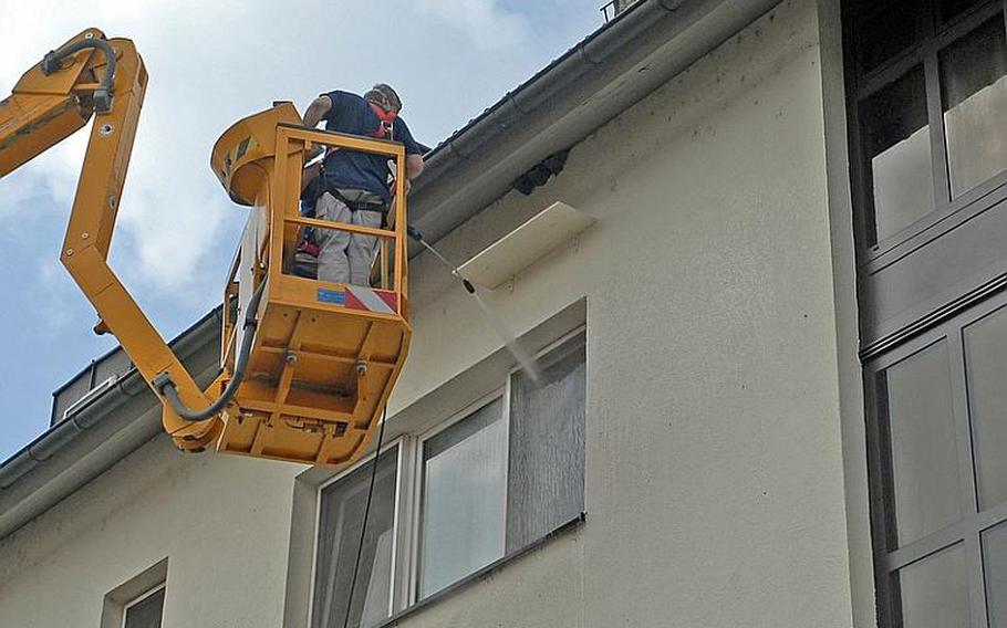 Workers for U.S. Army Garrison Baden Weurttemberg wash windows of a building on Patrick Henry Village last week after installing a board to catch droppings from nesting house martins. The birds' numbers have declined throughout Europe, and they and their nests, which they return to year after year, are protected in Germany and may not be removed. Six nests on the building were the first evidence of the birds' return to the area.