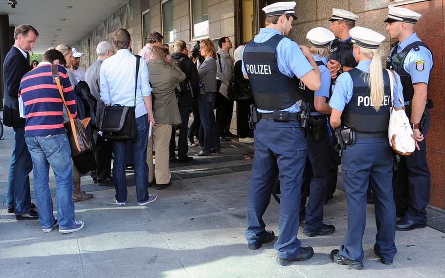 Police watch as spectators and the media line up to enter the Frankfurt, Germany, courthouse where the trial of Arid Uka started in August 2011. Uka is charged with two counts of murder for the slaying of Senior Airman Nicholas Alden and  Airman 1st Class Zachary R. Cuddeback at the Frankfurt Airport on March 2. Two other airmen were wounded in the attack.