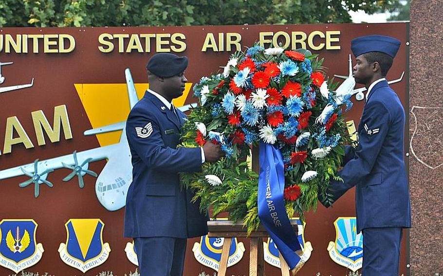 Two airmen remove a wreath from its pedestal during a ceremony Friday at Ramstein Air Base. The wreath, part of a ceremony commemorating 9/11, was placed at the foot of the flagpole, alongside another wreath that was brought by German officials.