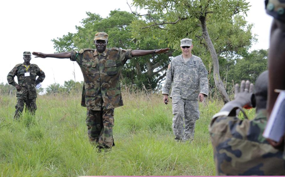 U.S. Army Cpl. James Carson, center, assists a Ugandan soldier during aerial resupply training at DZ Red near Kapelebyong, Uganda, April 14, 2011, during Atlas Drop 11. Atlas Drop is an annual joint aerial-delivery exercise sponsored by U.S. Army Africa that brings together Ugandan and U.S. Soldiers to enhance the readiness of both countries resupply and logistical capabilities. Carson is with Troop C, 3rd Squadron, 108th Cavalry Regiment, Georgia Army National Guard.  Both U.S. European Command and Africa Command depend on the Guard to carry out many key missions.