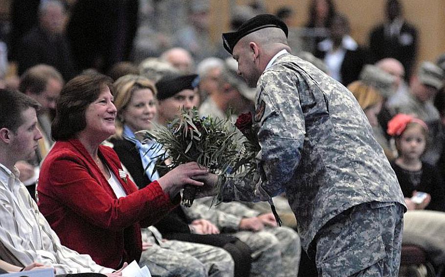 Staff Sgt. Larry Mills presents flowers to Carol Dill, wife of the outgoing commander of U.S. Army Garrison Wiesbaden, Germany. Col. Jeffrey Dill relinquished command of the garrison to Col. David Carstens on Jan. 12, 2012, during a ceremony at Wiesbaden Army Airfield.