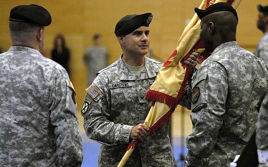 Col. David Carstens, center, passes the colors to Command Sgt. Maj. Hector Prince during a change-of-command ceremony at Wiesbaden Army Airfield, Germany, on Jan. 12, 2012.