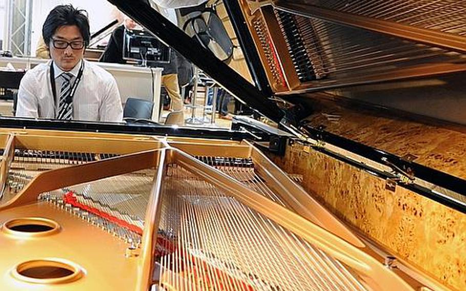 A grand piano gets tested March 21, 2012, by a visitor to Frankfurt's Musikmesse international music fair. With about 1,500 exhibitors, the fair is advertised as the largest of its kind in the world. It is open to the general public at Frankfurt's fairgrounds (Messe) on March 24, 2012. Admission is 20 euros, and tickets can be bought online.