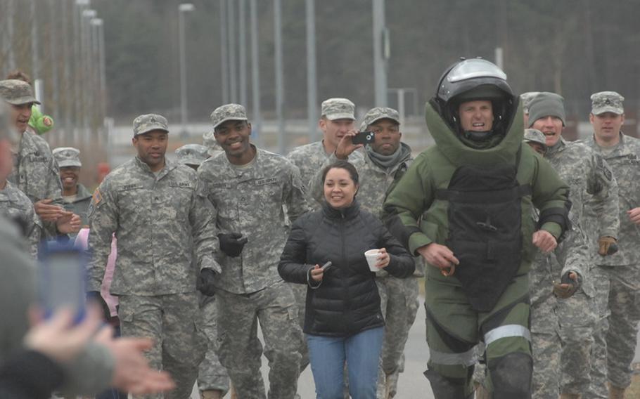 Army Sgt. 1st Class Eric Johnson of the 702nd Explosive Ordnance Detachment in Grafenwoehr, Germany, is joined Saturday by supporters as he nears the finish line in his effort to break the record for a one-mile run in a bomb suit. His time of 8 minutes, 5 seconds on March 31, 2012, which still must be certified, eclipsed the current record held by the World Records Academy, a time of 8:42 set by Johnson himself in 2010. It also appears to be the fastest time within the EOD community, Johnson said, besting a time of 8:30 the Navy said an ensign achieved earlier this year.
