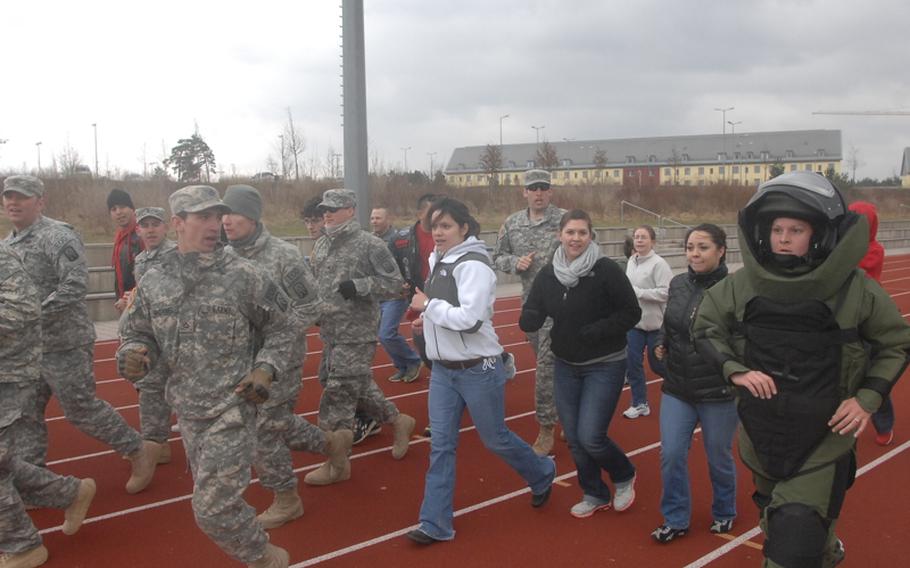 Sgt. Stephanie Beachley of the 702nd EOD is joined by supporters on the final lap of her attempt to set a world record for a one-mile run in a bomb suit at the Grafenwoehr track on March 31, 2012. Beachley will submit her time of 13 minutes, 14 seconds, to the Guinness Book of World Records.