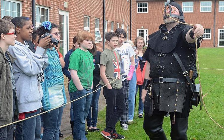At the Lakenheath Middle School?s U.K. Day on Friday, seventh-graders listen to a man portraying a medieval executioner as he demonstrates a device called a brank, which was used on women who nagged their husbands or gossiped too much.