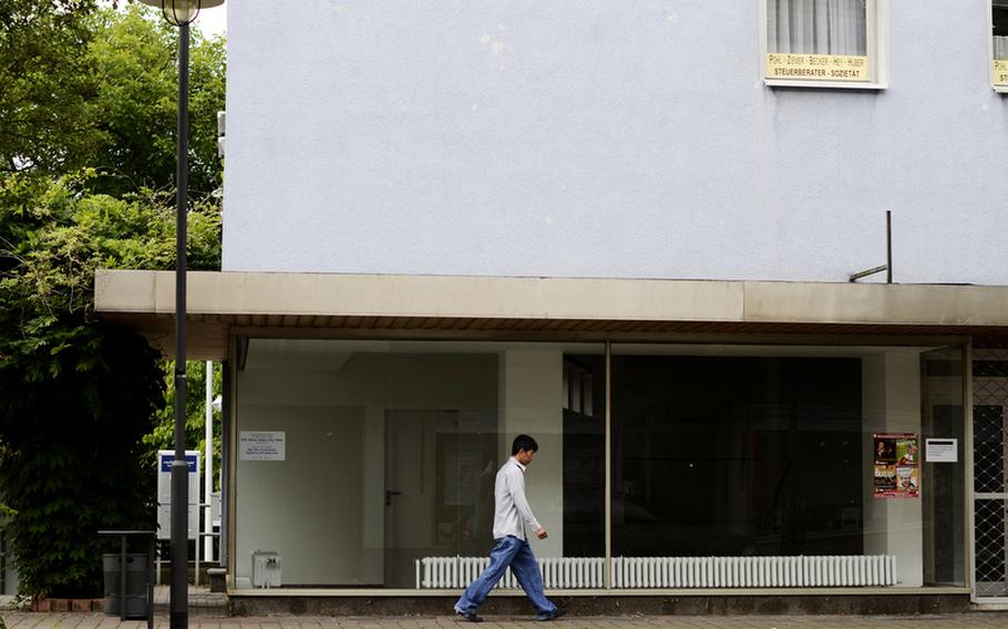 Mai Hien, owner of USA Nails, walks past an empty storefront in Baumholder, Germany.