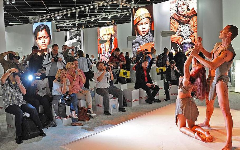 Armed with cameras in all shapes and sizes, visitors to Photokina in Cologne, Germany, take photos of dancers performing at the Sigma stand. The trade fair is billed as the world&#39;s largest for imaging.