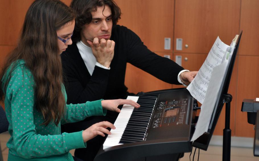 Esther Ruderman, one of the more accomplished piano players in a class at Vicenza Middle School, plays a song Feb. 8, 2013, while Italian concert pianist Davide Franceschetti listens and looks at the music. Franceschetti performed for students on base and then visited a few classrooms in the hopes of inspiring students to listen to classical music.