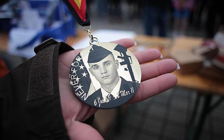 Air Force Staff Sgt. Monica Luna displays a medal bearing an image of slain Airman 1st Class Zachary Cuddeback, one of two airmen killed two years ago by a gunman who attacked a group of airmen bound for Afghanistan as they were boarding a bus at Frankfurt Airport. A run was held Saturday at Ramstein Air Base in honor of Cuddeback, who was driving the bus.