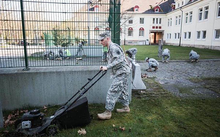 Soldiers with the 266th Financial Management Center in Kaiserslautern, Germany, mow the lawn, clean up leaves and clear weeds at Kleber Kaserne on Thursday, April 25, 2013. Soldiers around Europe spent the morning cleaning up bases as part of community spring cleanups.