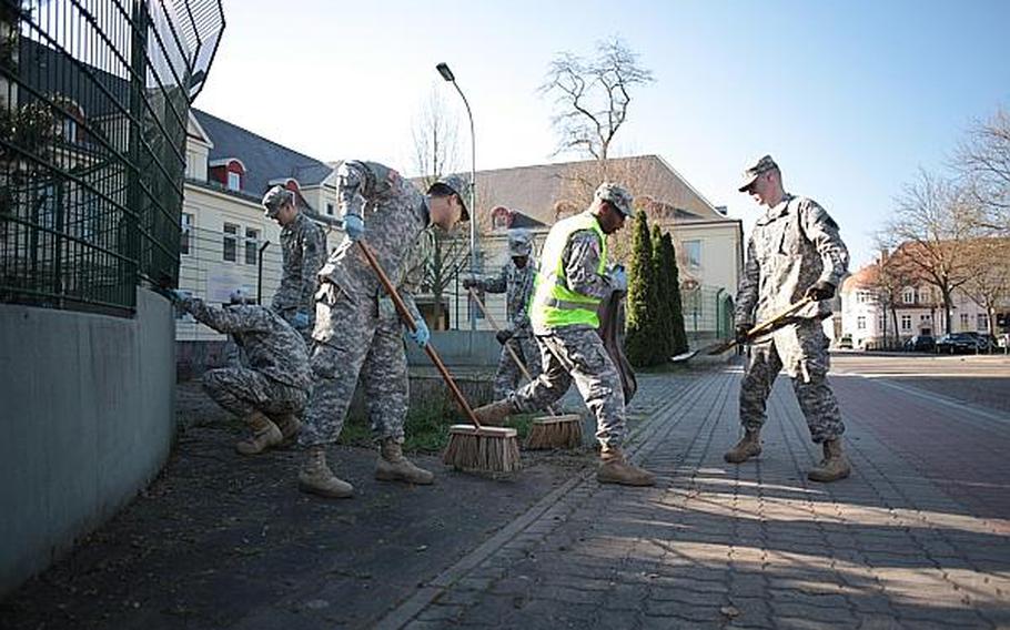 Soldiers with the 266th Financial Management Center in Kaiserslautern, Germany, remove grass and debris from the sidewalk April 25, 2013, outside Kleber Kaserne.