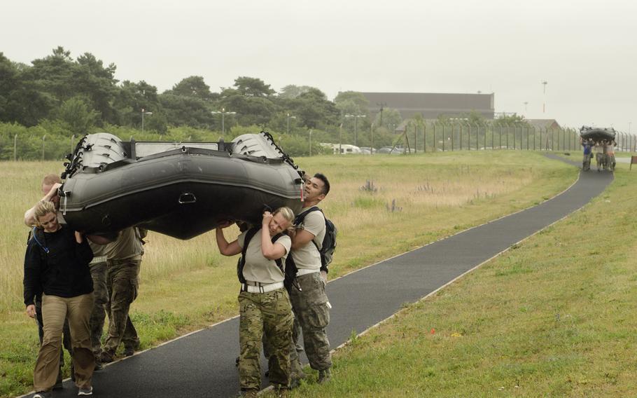 A Monster Mash team carries a small boat near the airfield at RAF Mildenhall, England, on Wednesday, July 3, 2013. Carrying various items --- large and small --- was a major part of the approximately seven-mile course.