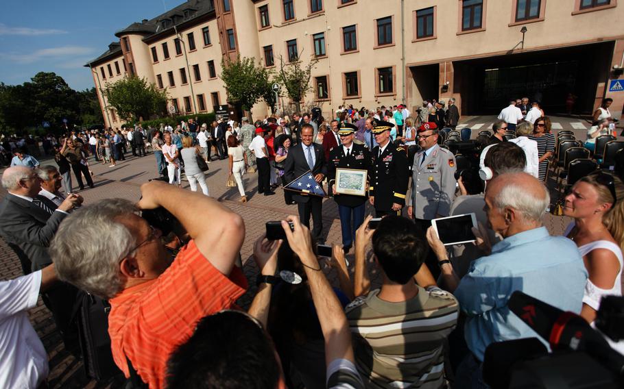 A crowd takes photos as German and American officials pose Friday with flags and other gifts presented to them at a ceremony marking the end of the U.S. Army presence in Heidelberg, Germany.