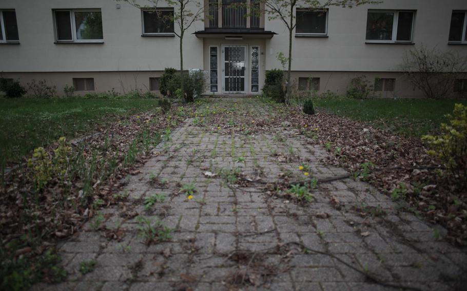 After sitting unoccupied for months, a sidewalk to a housing unit at the U.S. Army's Mark Twain Village in Heidelberg, Germany, is choked with weeds, leaves and twigs.