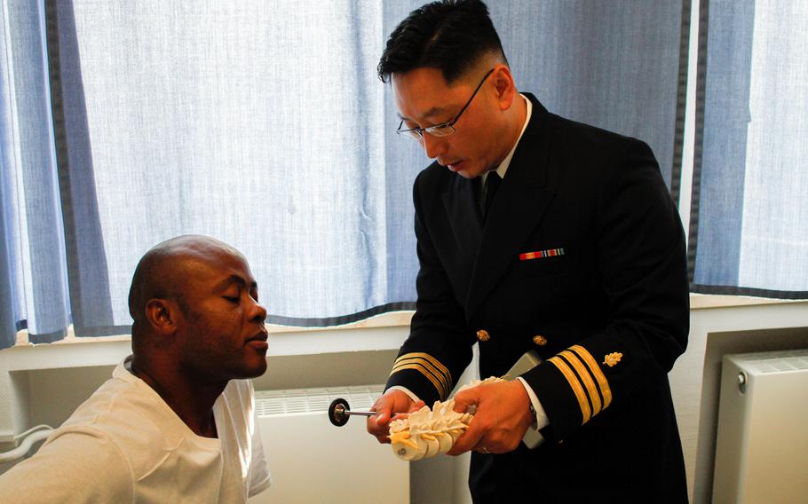 Navy Cmdr. Kendall Lee, right, explains to Army chaplain (Capt.) Thomas Obiatuegwu what's causing the Catholic priest's debilitating back pain. Lee, a Korean immigrant, joined the Navy Reserve at the age of 42 as a neurosurgeon, in part to repay his adopted country for the opportunities it provided him and his family.