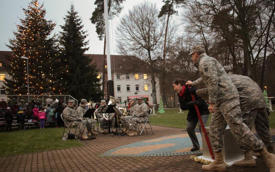 Maj. Gen. John O'Connor, commander of the 21st Theater Sustainment Command, along with Amy Rodick and Sgt. Baran Pourtahmaseb-Sasi flip a giant switch at a holiday tree lighting ceremony Wednesday, Dec. 4, 2013, at Panzer Kaserne in Kaiserslautern, Germany.