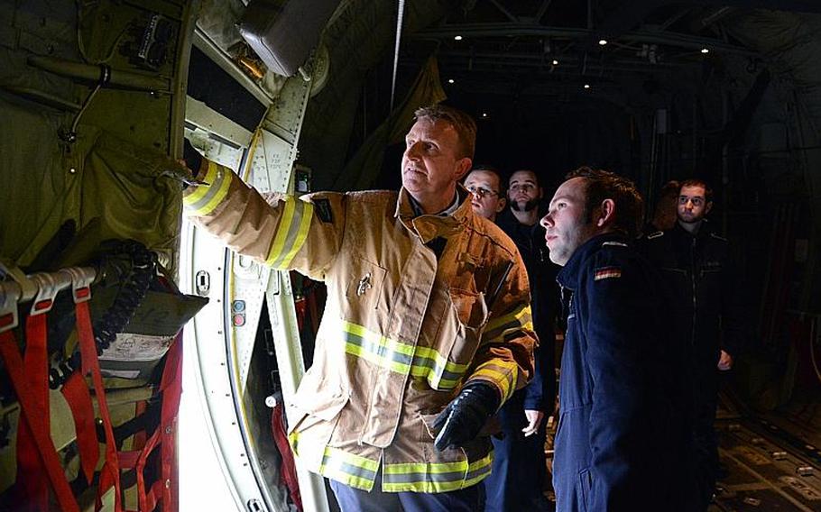 Station Capt. Klaus Rupp, of Kaiserslautern Military Community Fire Department's Fire Station No. 1, shows German soldiers from the 8th Kompanie, Spezialpionierbatallion 464 how an emergency exit on a U.S. Air Force C-130 Hercules works.