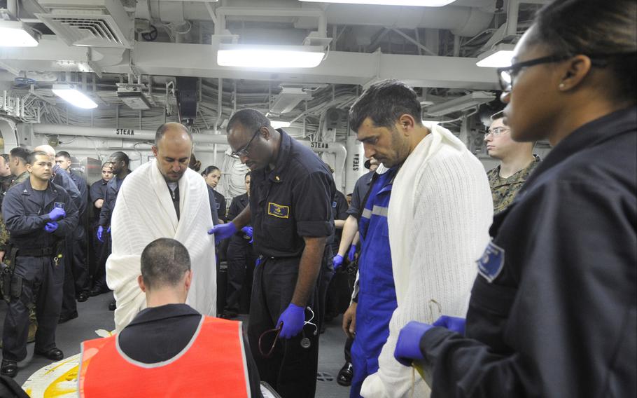 Sailors aboard the amphibious assault ship USS Bataan assess two Turkish mariners recovered by a Navy search-and-rescue team from a wrecked ship off the coast of Mykonos in the Aegean Sea on March 8, 2014.