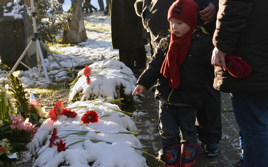 A Belgian boy points to flowers left by school children during a ceremony marking the 70th anniversary of the Malady massacre Sunday, Dec. 14, 2014. On Dec.17, 1944, in Baugnez, Belgium, Nazi SS troops killed 84 American prisoners of war during the Battle of the Bulge. Baugnez is a suburb of Malmedy.